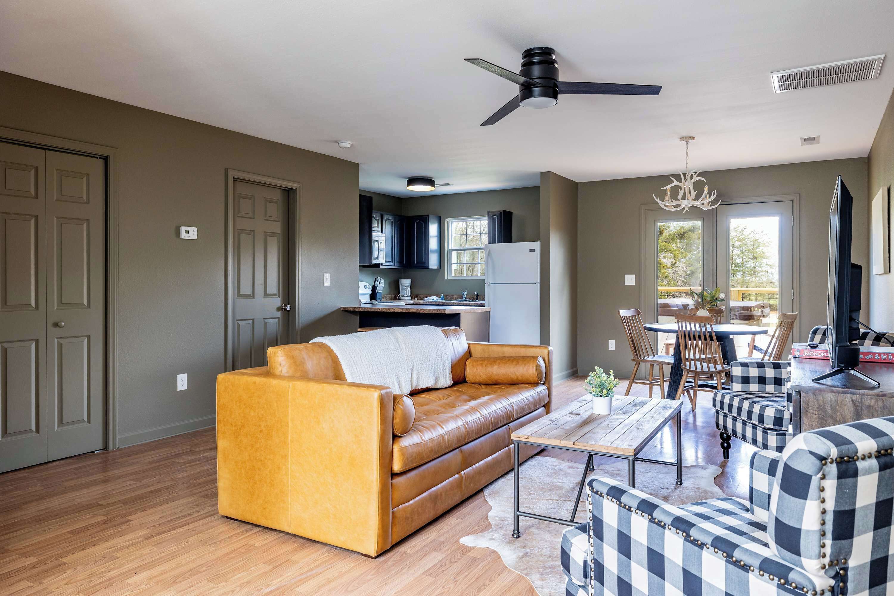 A modern living room with a leather sofa, a coffee table, and a dining area with chairs and a table.