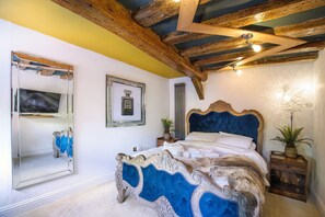 Ein Schlafzimmer mit einem großen Bett, einem Spiegel, einem gerahmten Bild und einer Holzbalkendecke.