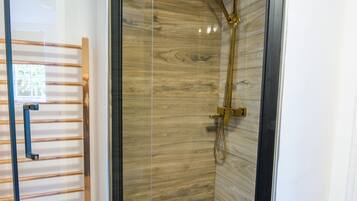A glass-enclosed shower with a wooden interior, a metal showerhead, and a handheld shower attachment.