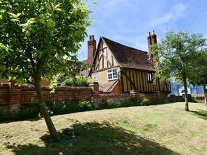 Ein traditionelles Haus im Tudor-Stil mit Ziegelmauer, Strohdach und Schornsteinen.