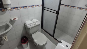 Un baño con inodoro, lavamanos y zona de ducha.