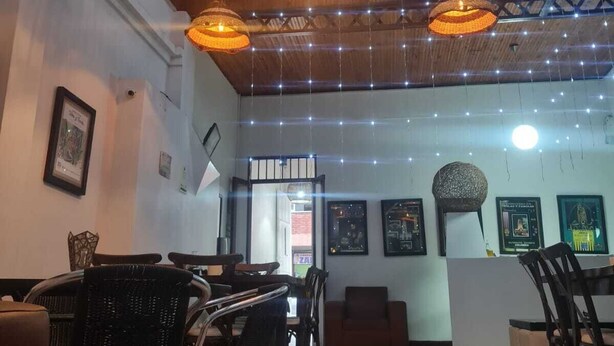 Interior de un restaurante con lámparas de mimbre colgantes, baldosas de suelo estampadas y obras enmarcadas en las paredes.