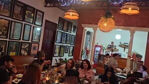 Un restaurante con varias mesas, cuadros en las paredes y lámparas colgantes.