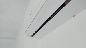 Unidade de ar condicionado branca, com etiqueta verde e painel de controle preto.
