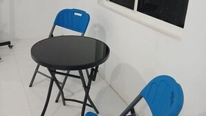 Um quarto pequeno com uma mesa redonda e duas cadeiras azuis.