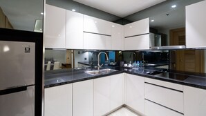A modern kitchen with white cabinets, a stainless steel sink, and a black countertop.