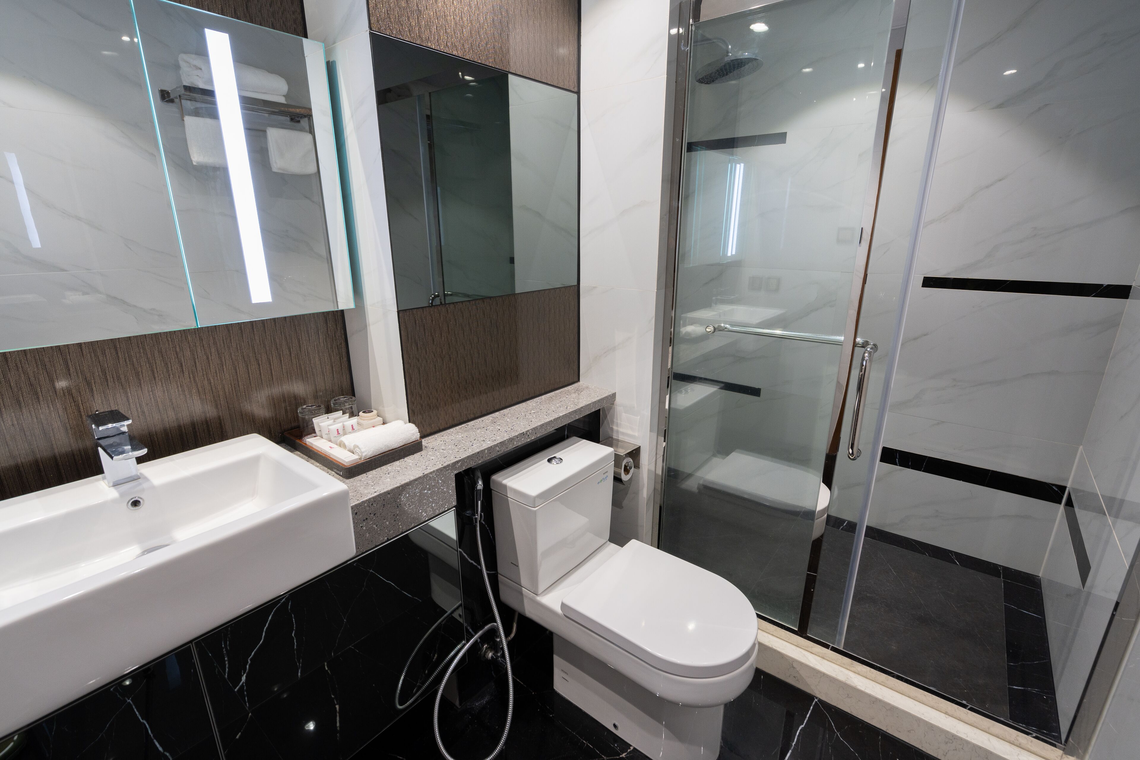 Une salle de bain moderne avec un lavabo blanc, des toilettes et une douche à parois de verre.