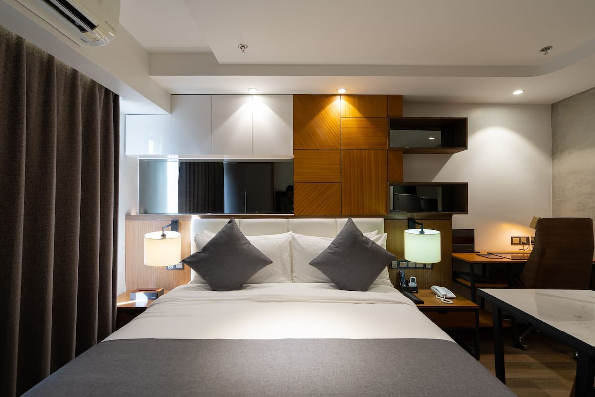 Ein modernes Hotelzimmer mit einem großen Bett, Nachttischen, einem Schreibtisch und einem Sessel.
