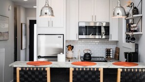A modern kitchen with white cabinets, stainless steel appliances, and pendant lighting.