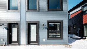 A modern two-story building with a dark gray exterior, two front doors, and multiple windows.