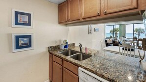 A kitchen with granite countertops, wooden cabinets, and a built-in dishwasher.