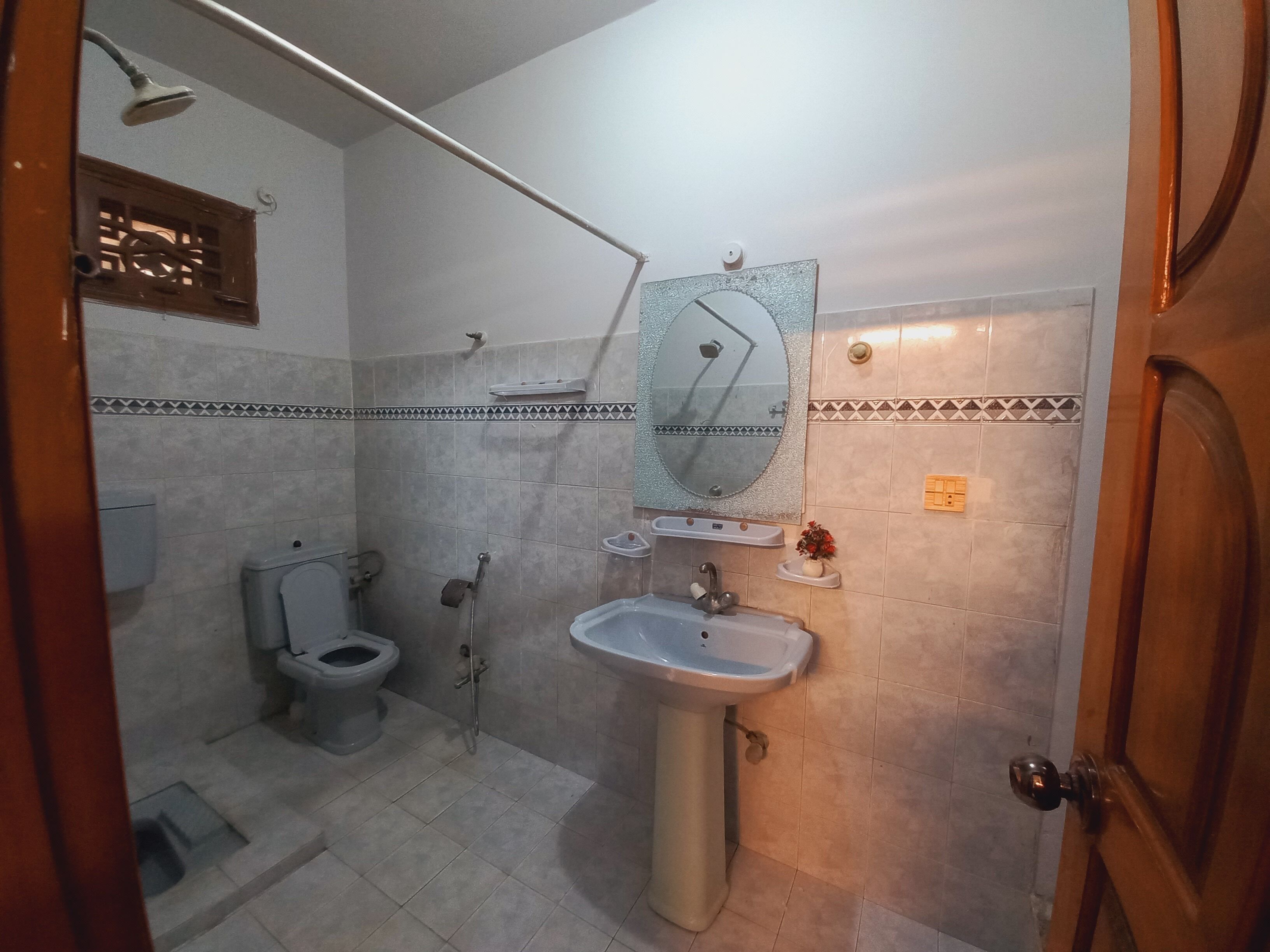 A bathroom with a toilet, shower, sink, and mirror.