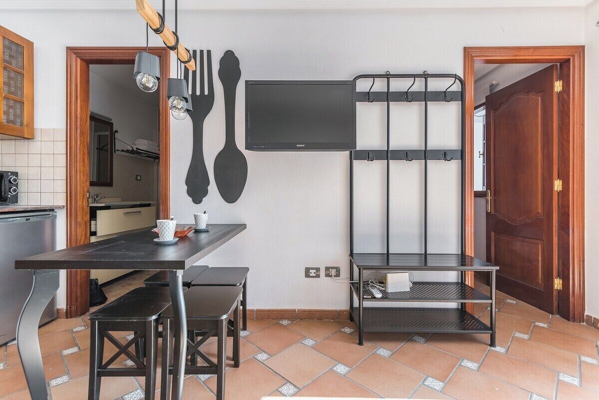 Een kleine keuken met een eettafel, stoelen en een tv aan de muur.