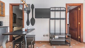 A compact kitchen with a dining table, chairs, and a wall-mounted TV. - Home2Book Charming Attic El Rincón de Telde, BBQ (Telde)
