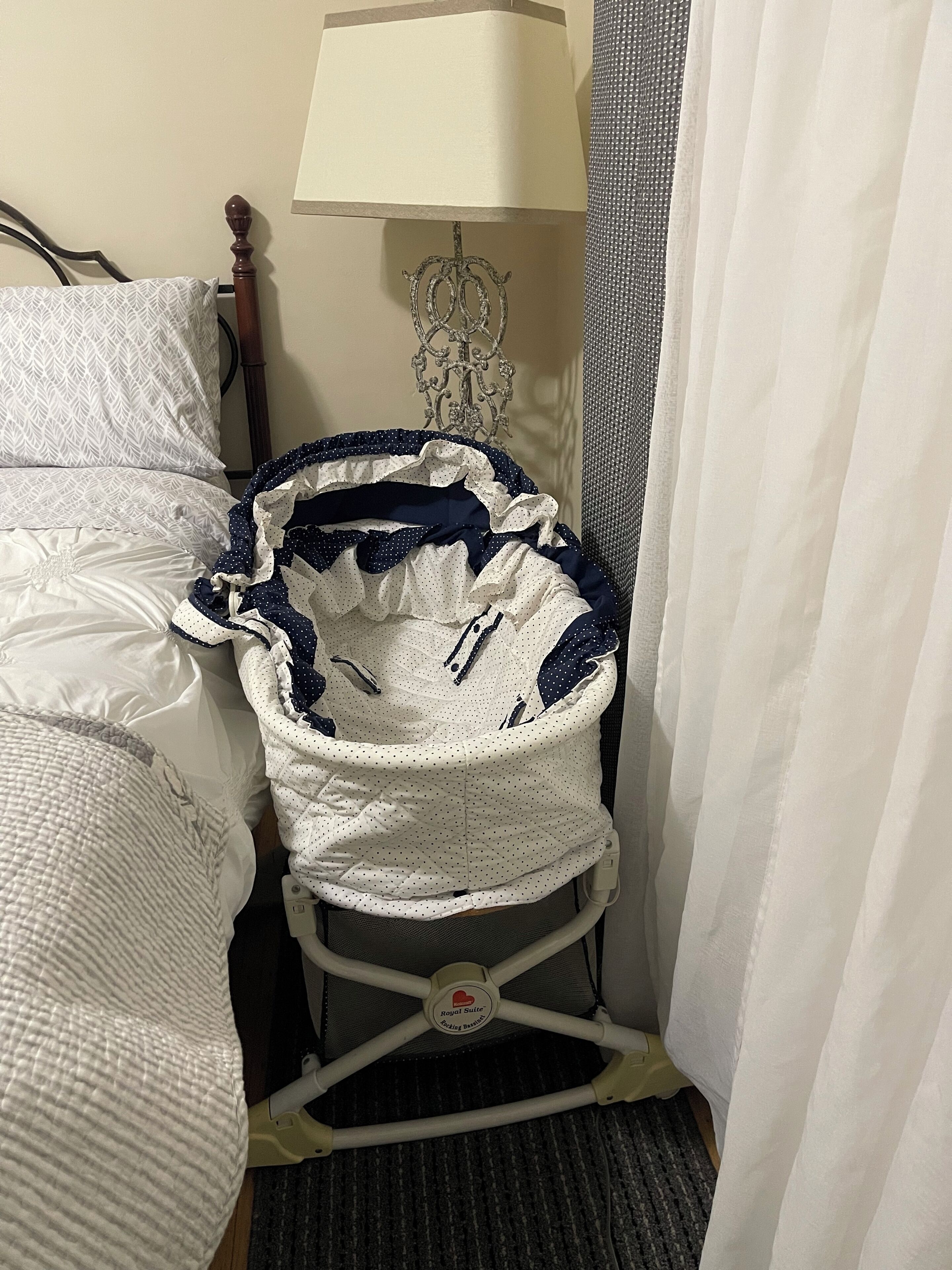 Een kinderwagen met een wit en marineblauw design, een lamp en een bed met beddengoed met een patroon.