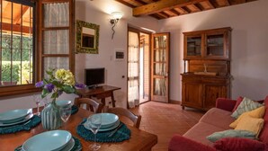 A dining area with a wooden table set for four, a television, and a cabinet in the background. - Vacation home Salvia by Interhome (Massa Marittima)