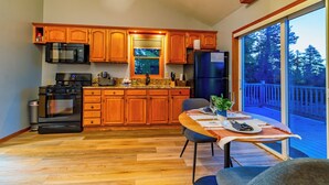 A modern kitchen with wooden cabinets, a black stove, and a dining area with a table and chairs.