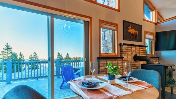 A dining area with a table set for two, a fireplace, and a view of the outdoors.