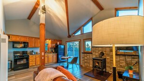 A spacious living area with a fireplace, a dining table with chairs, and a kitchen area with wooden cabinets and appliances.