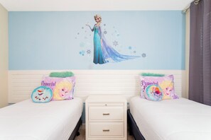 A bedroom with two beds, each with a decorative pillow featuring a character.