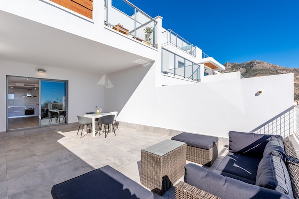 Un patio moderno al aire libre con comedor, asientos y vistas del paisaje circundante.