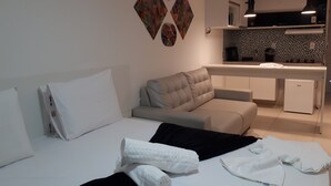 A modern hotel room with a bed, a sofa, a small kitchenette, and a dining area. - Miramar Laguna Beach (Ipojuca)