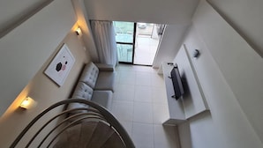 A modern interior with a staircase, a sofa, and a TV mounted on the wall. - Miramar Laguna Beach (Ipojuca)