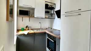 A compact kitchen with a microwave, oven, and sink. - Happy Family Apartments Lanterna (Genoa)