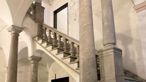 A grand staircase with marble columns and balustrades, leading to an upper level. - Happy Family Apartments Lanterna (Genoa)