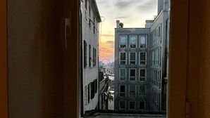 A window with a view of a cityscape at sunset. - Happy Family Apartments Lanterna (Genoa)