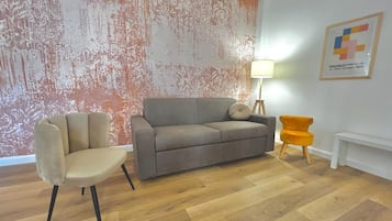 Relax in this stylish living room with a sofa, armchair, and vibrant chair, surrounded by a textured wallpaper and artwork.