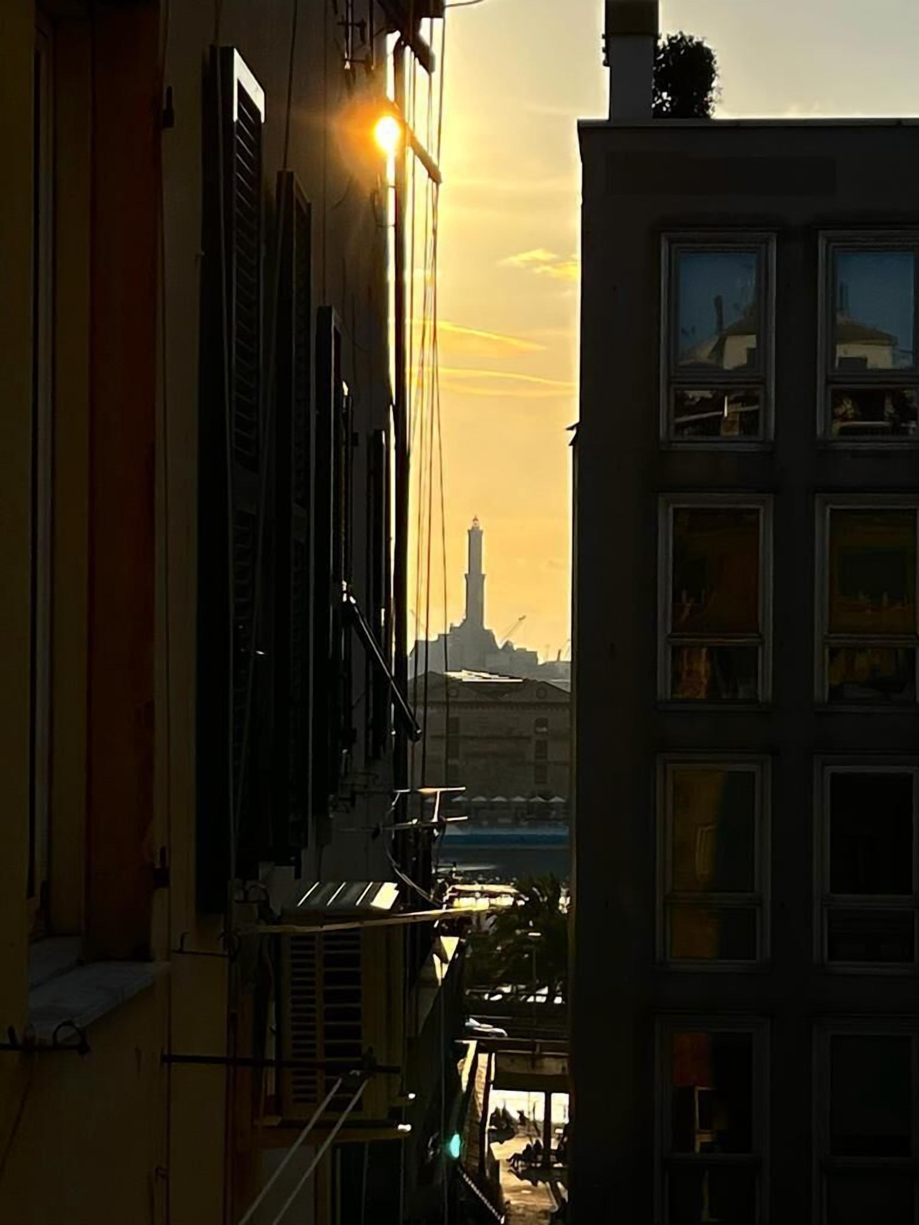 Un edificio con vista su una torre lontana e un tramonto.