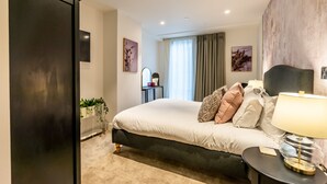 Una camera da letto moderna con un letto grande, comodini, un armadio e vista sull'esterno attraverso una finestra.