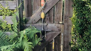 Un cancello di legno con una boa appesa, immerso nel verde e felci.