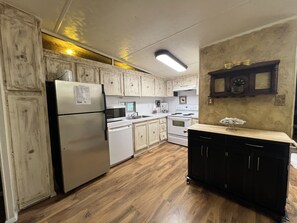 A kitchen with white cabinets, a refrigerator, a microwave, a stove, and a sink. - Mountain Harbor's four bedroom house by RedAwning (Mount Ida)