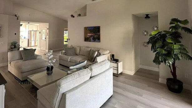 A spacious living room with a large sofa, a coffee table, and a ceiling fan. - Home in Kissimmee (Kissimmee)