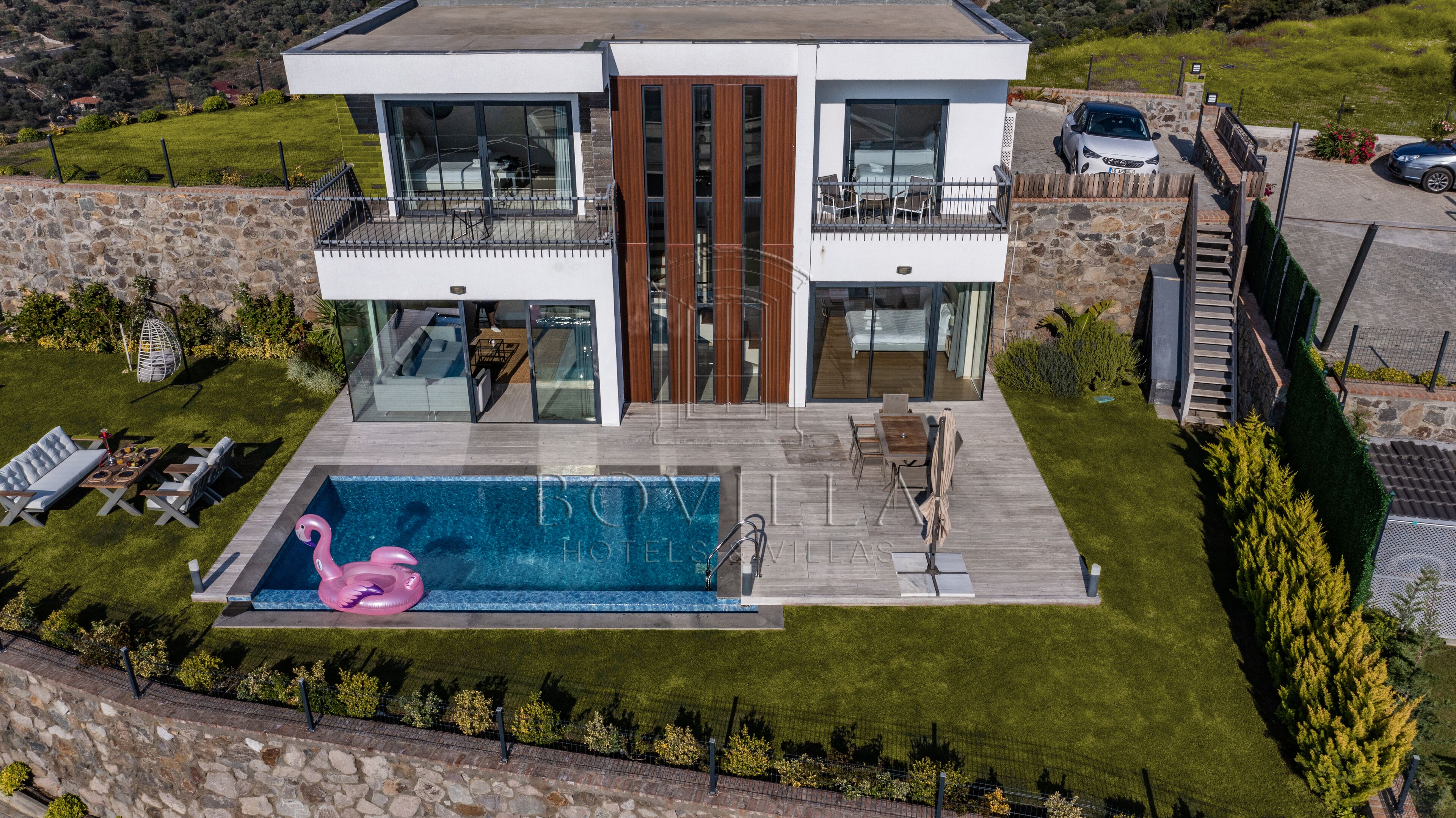 A modern two-story house with a swimming pool, a balcony, and a driveway.