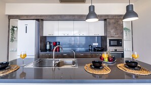 A modern kitchen with stainless steel appliances, a central island with a sink, and pendant lighting.