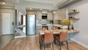A modern kitchen with a built-in island, stainless steel appliances, and a dining area with wooden chairs. - Sirius Town Residence and Spa (Antalya)