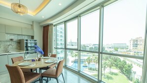 A modern dining area with a large window overlooking a cityscape and a swimming pool. - Sirius Town Residence and Spa (Antalya)