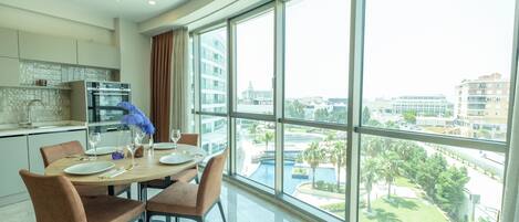 Un área de comedor moderna con un amplio ventanal con vistas a un paisaje urbano y una piscina.