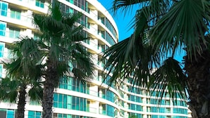 A modern hotel with a curved facade, palm trees, and a pool area. - Sirius Town Residence and Spa (Antalya)