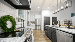 A modern kitchen with a stainless steel refrigerator, a built-in oven, and a dishwasher. - Cozy, Game Deck, Outdoor Swing, 2 King Suites, Save 7% in Taxes! (Broken Bow)
