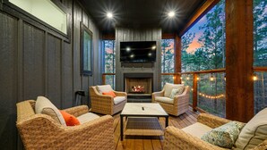 A cozy outdoor seating area with wicker furniture, a flat-screen TV, and a fireplace. - Cozy, Game Deck, Outdoor Swing, 2 King Suites, Save 7% in Taxes! (Broken Bow)