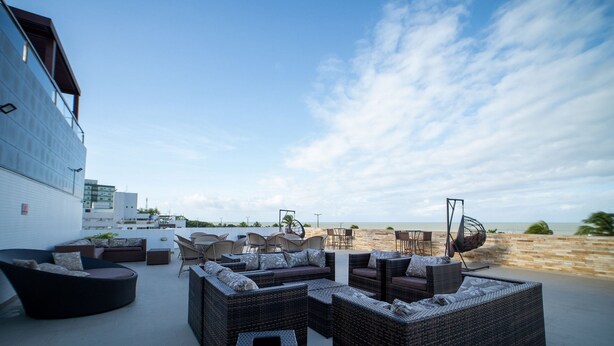Een terras met rieten meubels en uitzicht op het strand.