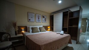 Een hotelkamer met een bed, nachtkastjes, een stoel, een bureau, een kledingkast en kunst aan de muur.