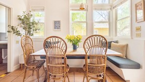 Un coin repas comprenant une table, des chaises en osier, un banc et une plante en pot.