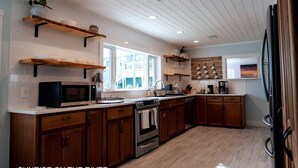 Une cuisine moderne avec des meubles en bois, un four à micro-ondes encastré et une grande fenêtre qui laisse entrer la lumière naturelle.