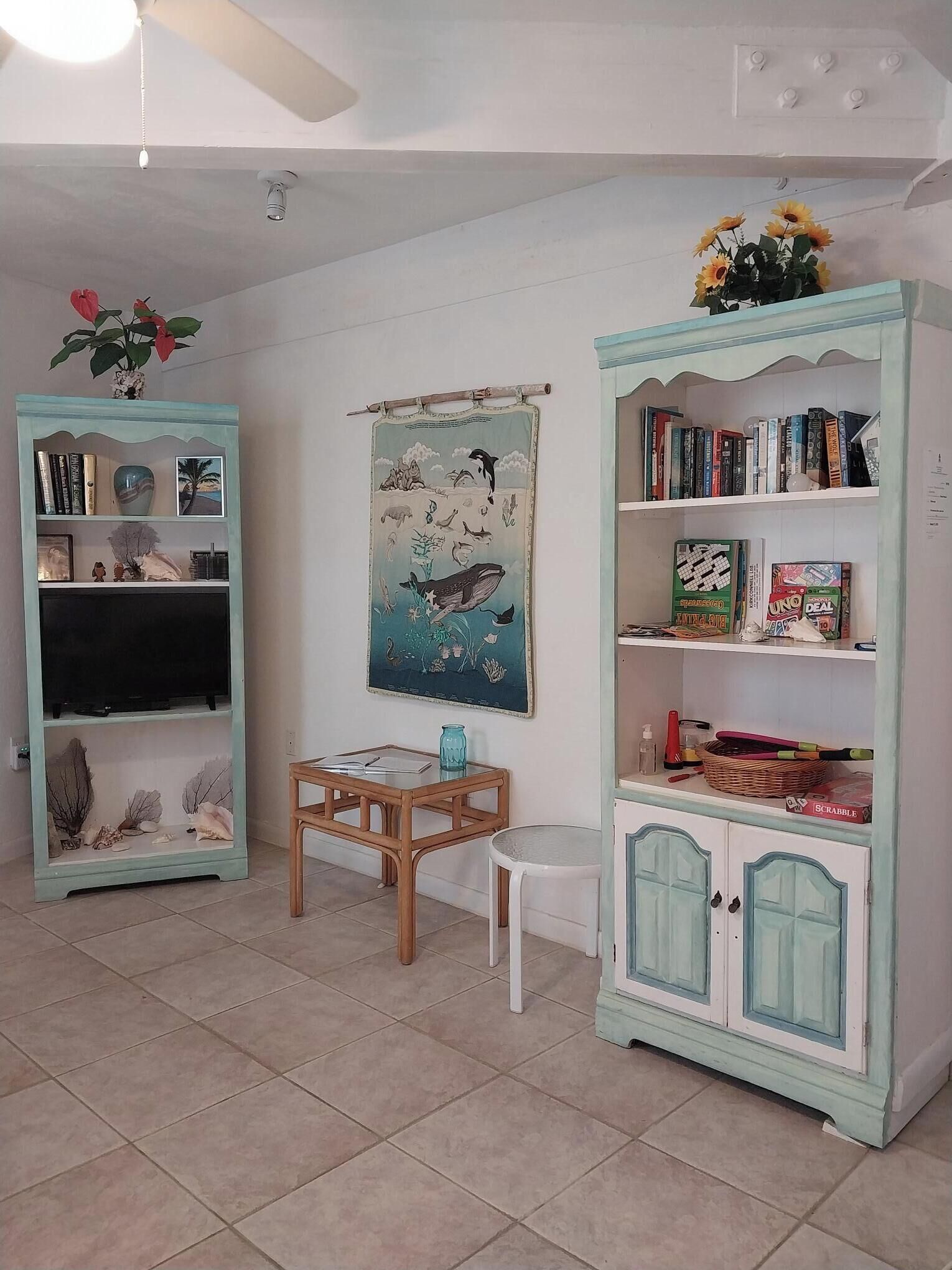 Une pièce comprenant deux étagères de couleur turquoise, une petite table, un meuble blanc et une décoration murale.