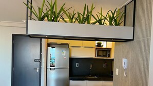 A compact kitchen with a refrigerator, microwave, and a small dining area with a table and chairs. - Miramar One Way Tambaú (João Pessoa)